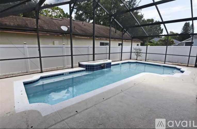 A pool enclosed by a black fence with trees in the background.