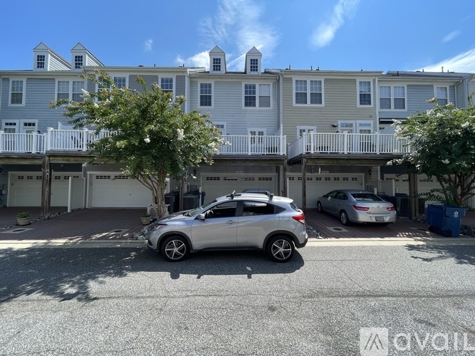 A silver car is parked in front of a two-story apartment building.