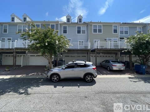 A silver car is parked in front of a two-story apartment building.