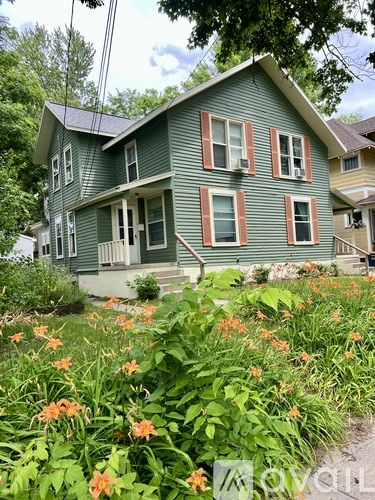A green house with a porch and a small garden in front.