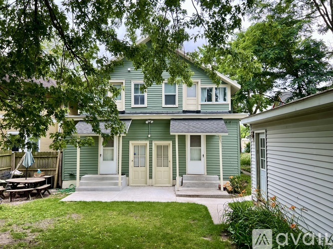 A green house with a white door and a small porch.