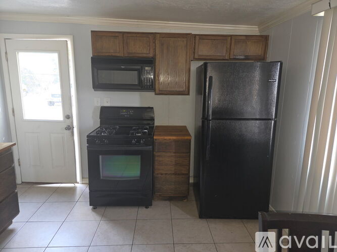 A black refrigerator sits in a kitchen next to a black stove.