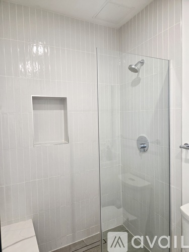 A white tiled bathroom with a glass shower door.