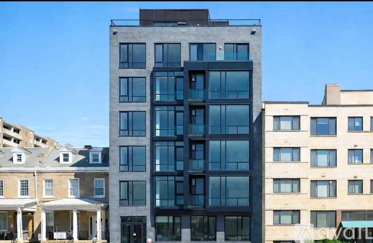 A modern glass building stands between two older buildings.