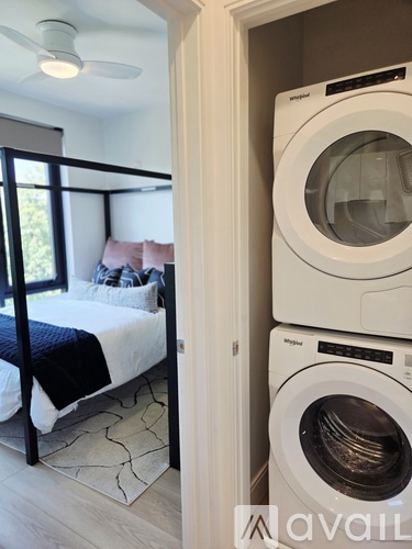 A bedroom with a bed and a washing machine in the corner.