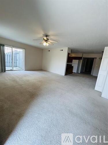 A room with a ceiling fan and carpeted floor.