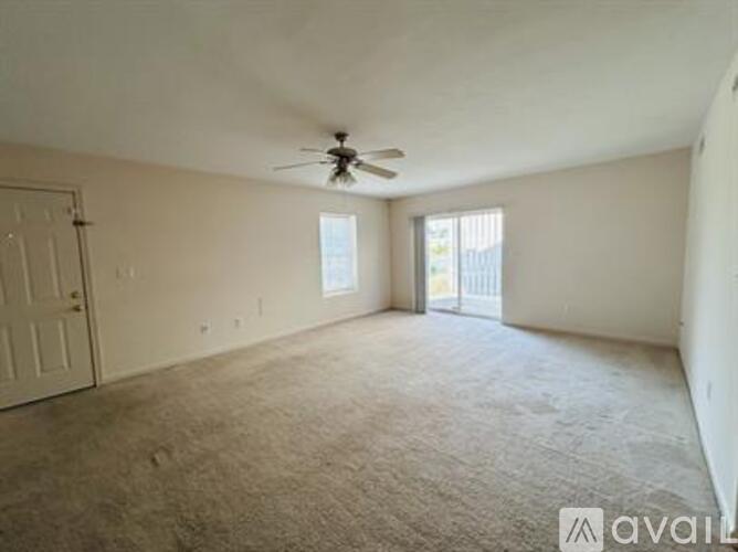 A spacious room with a ceiling fan and carpeted floor.