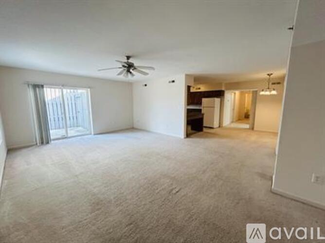 A spacious living room with a ceiling fan and carpeted floor.