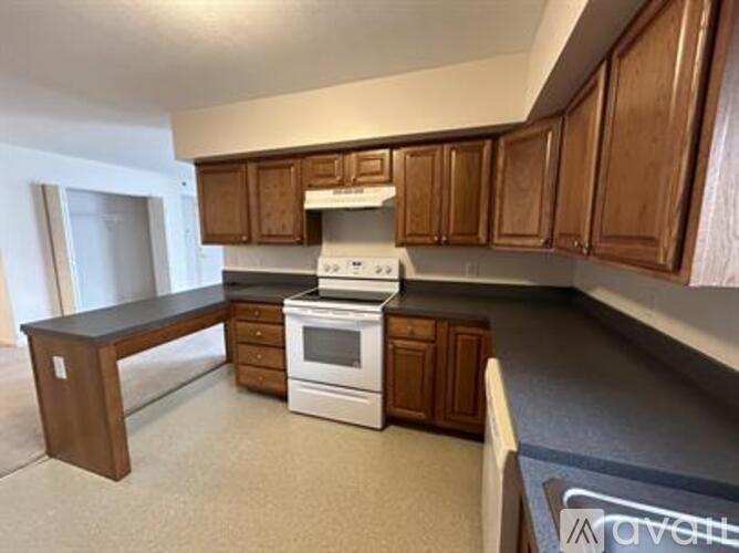 A kitchen with wooden cabinets and a white stove top oven.