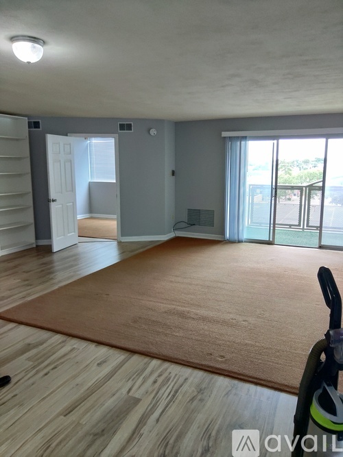 A room with wooden flooring and a rug in the foreground.