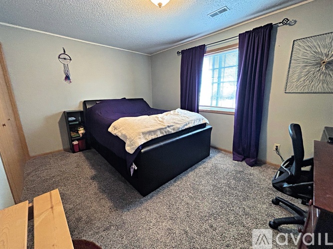 A bedroom with a bed, desk, and chair.
