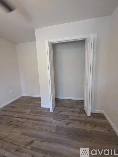 A room with a white door and wooden flooring.