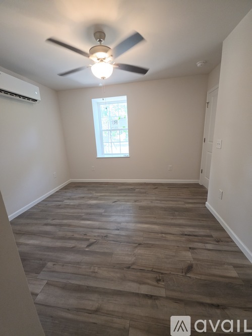 A room with wooden flooring and a ceiling fan.