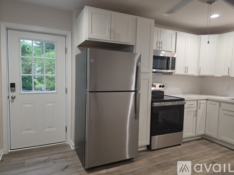 A modern kitchen with a stainless steel refrigerator and white cabinets.
