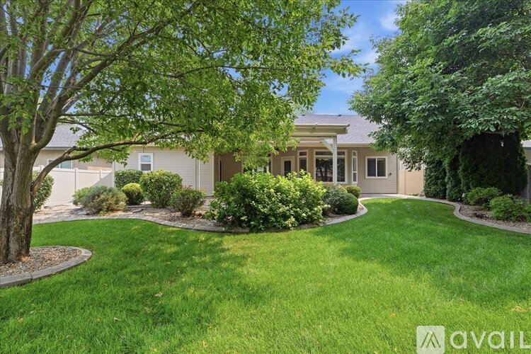 A house with a well-manicured lawn and trees in front.