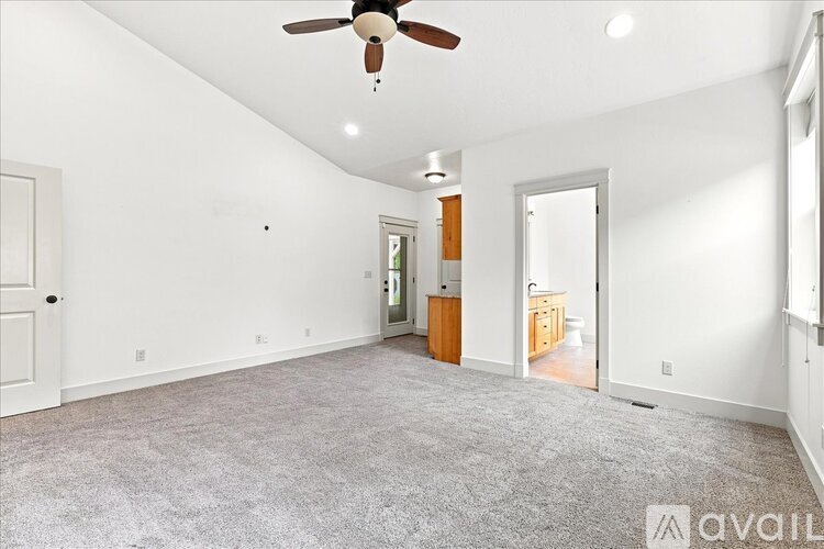 A spacious room with a ceiling fan and carpeted floor.