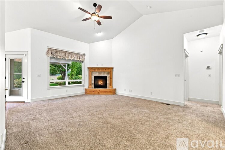 A spacious living room with a fireplace and a ceiling fan.