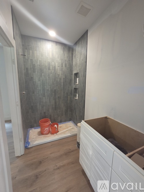 A bathroom with a grey tiled wall and a white cabinet.