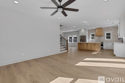 A spacious living room with a ceiling fan and lighting fixtures.