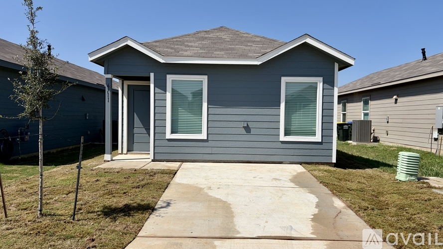 A grey house with a brown roof and a white door.