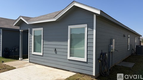 A grey house with a white window and a hose on the wall.