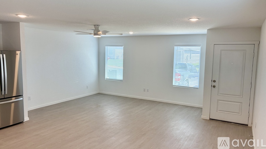A spacious room with a refrigerator on the left and a door on the right.