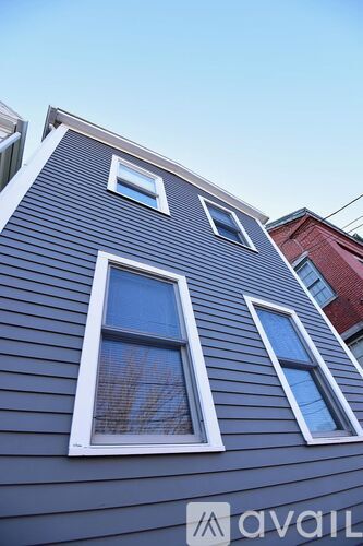 A house with a grey siding and three windows.