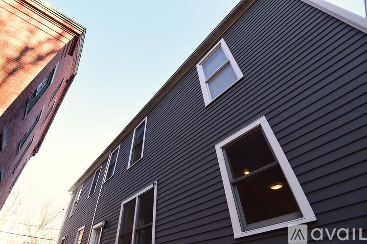 A building with a dark grey siding and a white window is shown.