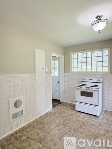 A kitchen with a white stove and tiled walls.
