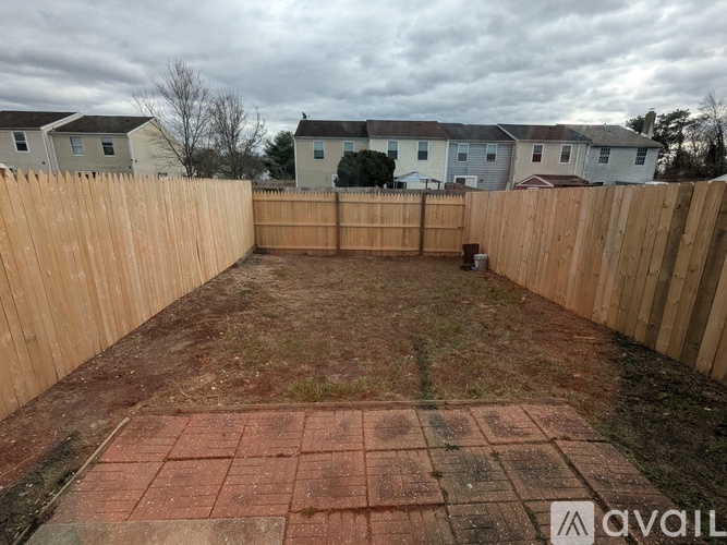 A backyard with a wooden fence and a brick patio.