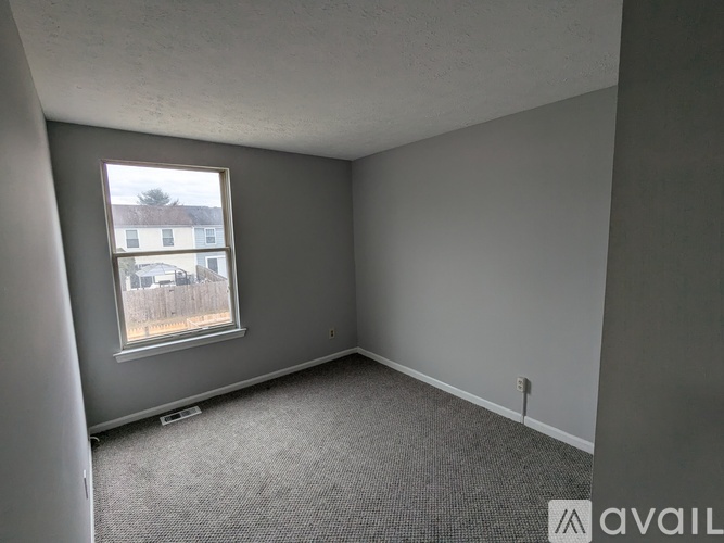 A room with grey walls and a window showing a view of a building outside.