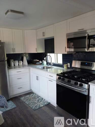 A kitchen with white cabinets and black appliances.