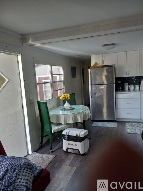 A kitchen with a fridge, stove, and a table with a vase of flowers on it.