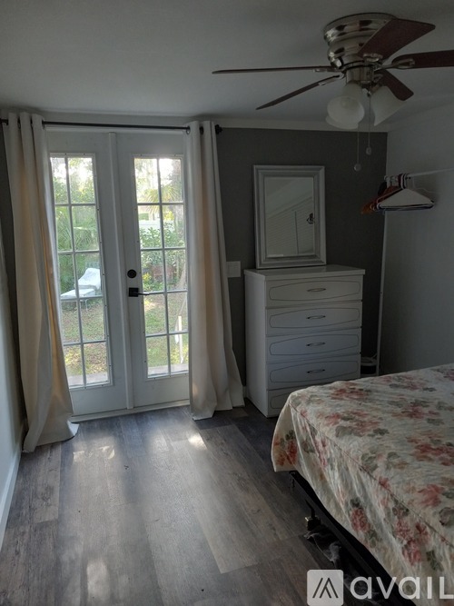 A bedroom with a bed, dresser, and window with curtains.
