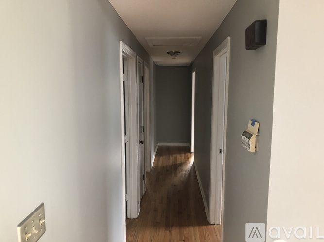 A hallway with a door on the right and a wall socket on the left.
