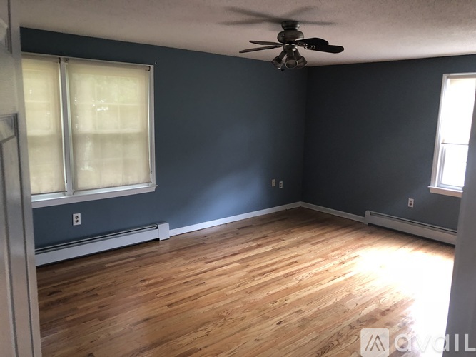 A room with a ceiling fan and wooden flooring.