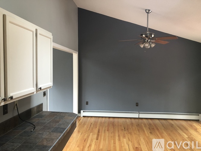 A room with a ceiling fan and wooden flooring.