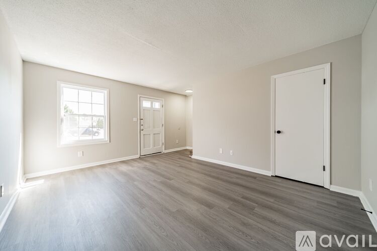 A spacious room with wooden flooring and white walls.