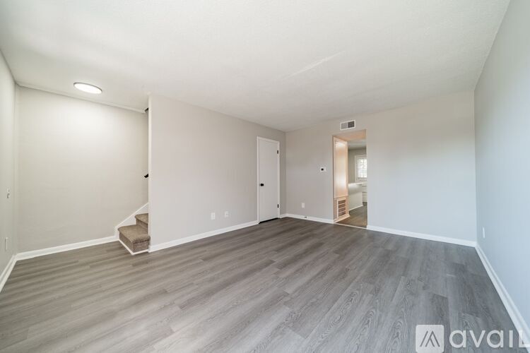 A spacious room with wooden flooring and white walls.