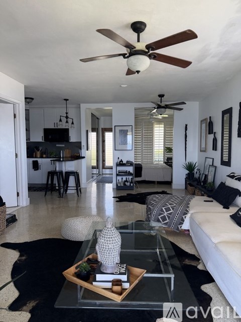 A living room with a black cowhide rug and a glass coffee table with a tray on it.