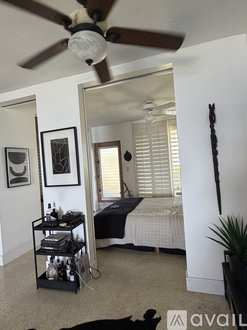 A bedroom with a bed, a ceiling fan, and a mirror.