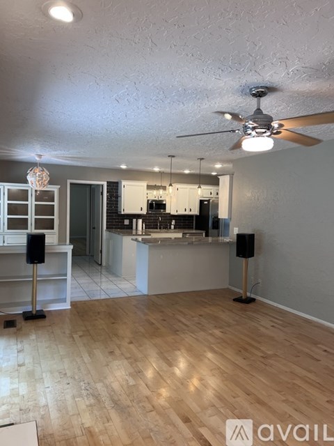 A room with a ceiling fan and wooden flooring.