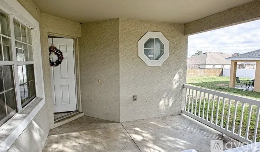 A balcony with a white door and a wreath hanging on the door.
