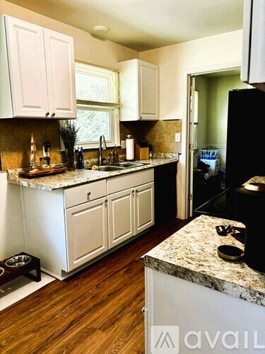 A kitchen with white cabinets and a granite counter.