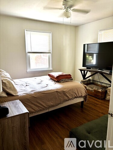 A bedroom with a bed, a television, and a window.