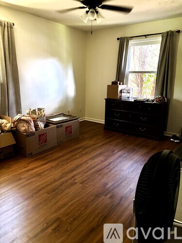A room with a ceiling fan and a dresser with boxes on the floor.