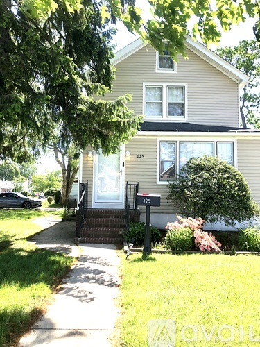 A house numbered 125 with a front yard and a tree.