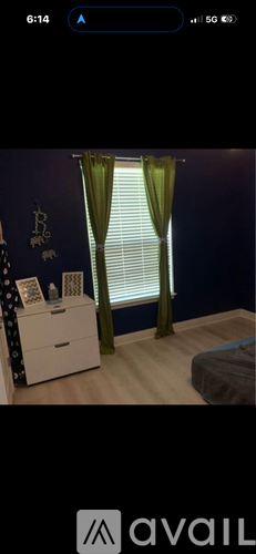 A room with a window covered by green curtains.
