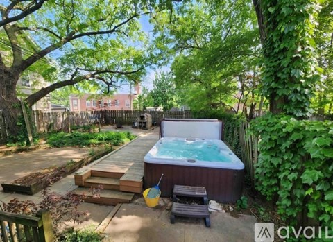 A hot tub sits in a backyard surrounded by greenery.