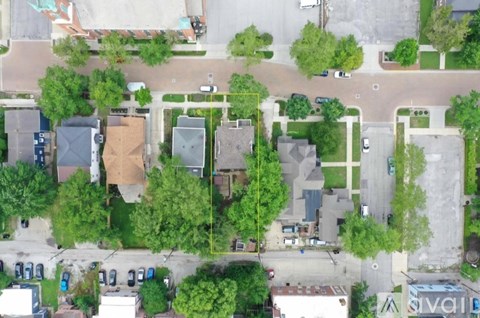 A bird's eye view of a residential area with houses, trees, and a parking lot.